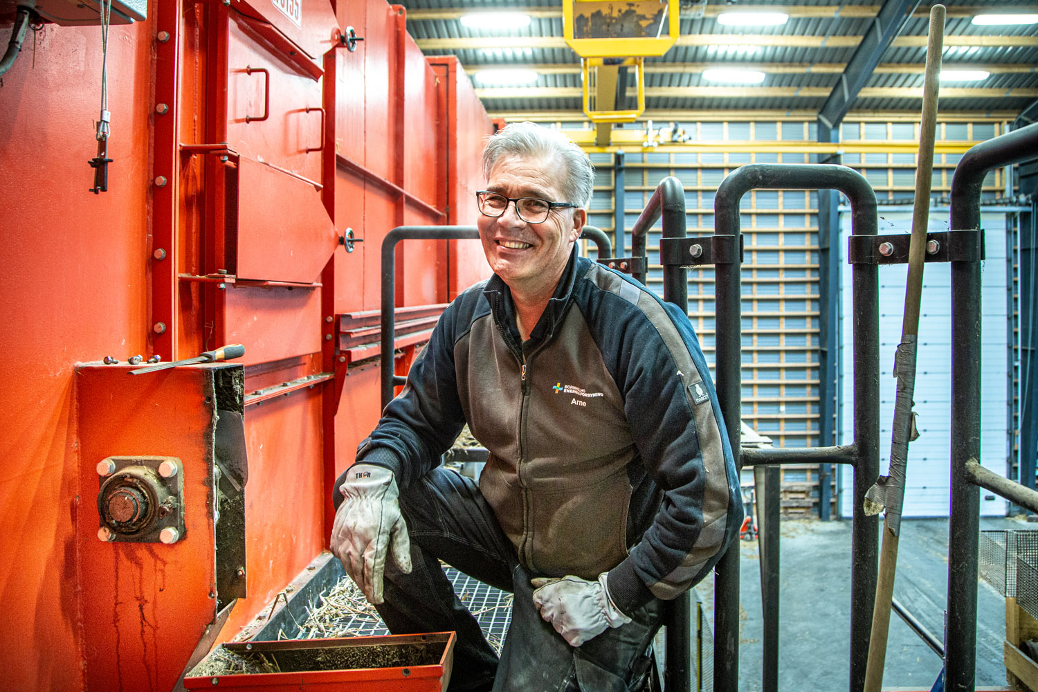 Medarbejder foran stor maskine, som håndtere halm til fjernvarme